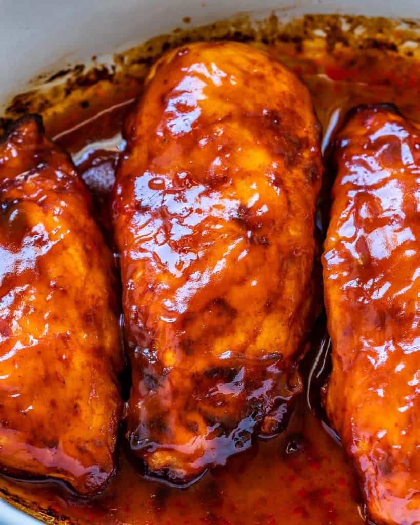 Up close view of baked BBQ chicken breast covered in BBQ sauce.