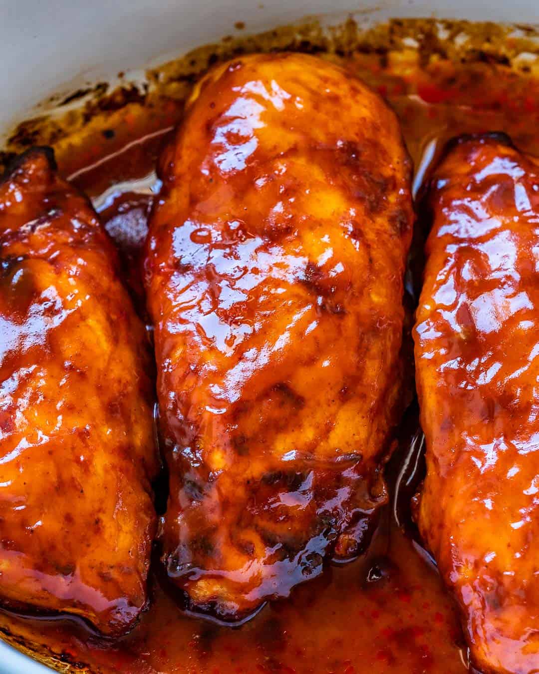 Up close view of baked BBQ chicken breast covered in BBQ sauce. 