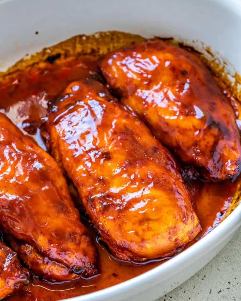 side shot of baked bbq chicken breast in white dish