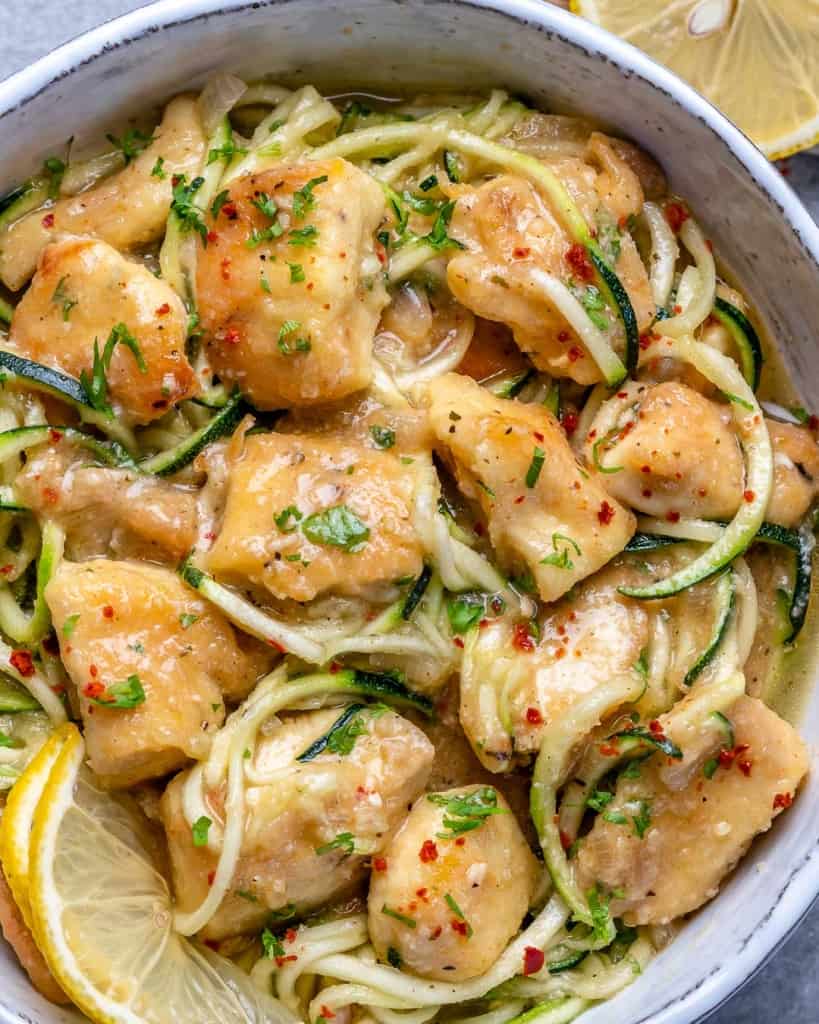 close up chicken scampi with zoodles, lemon garnish and chili pepper flakes.
