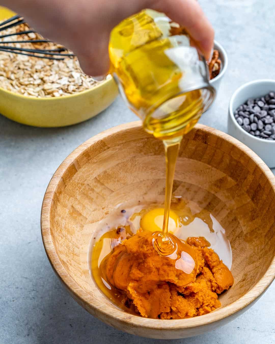 pumpkin puree and eggs in brown bowl, honey being poured over them