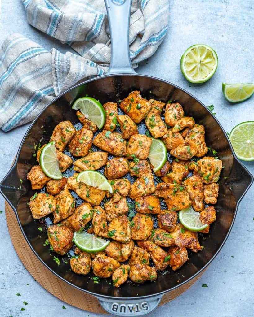top view chicken bites in a skillet with lime wedges