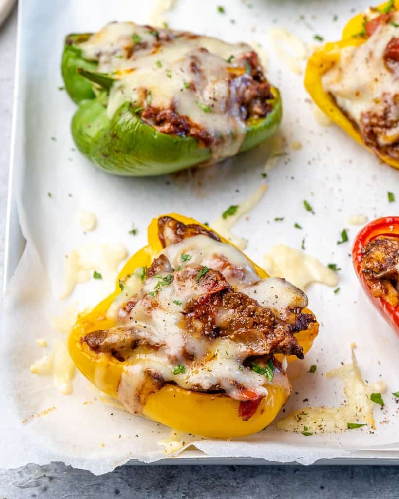 Red, green and yellow taco stuffed peppers on a baking sheet. 