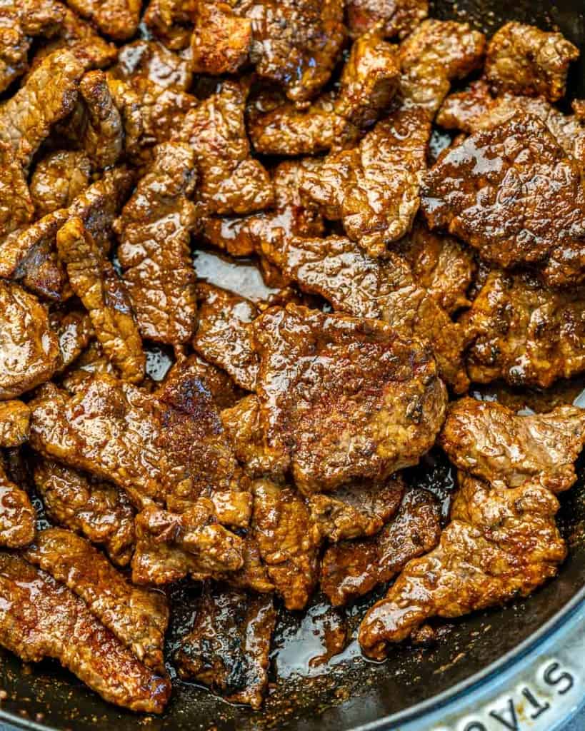 Top down view of steak cooking in a skillet. 