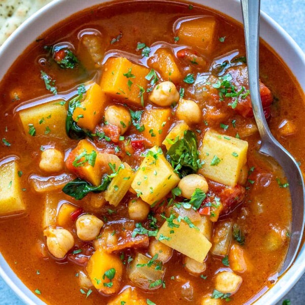 veggie soup in a white bowl with spoon in bowl.