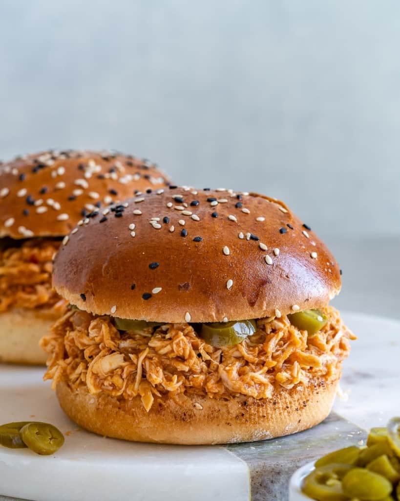 Two pulled chicken burgers on white surface