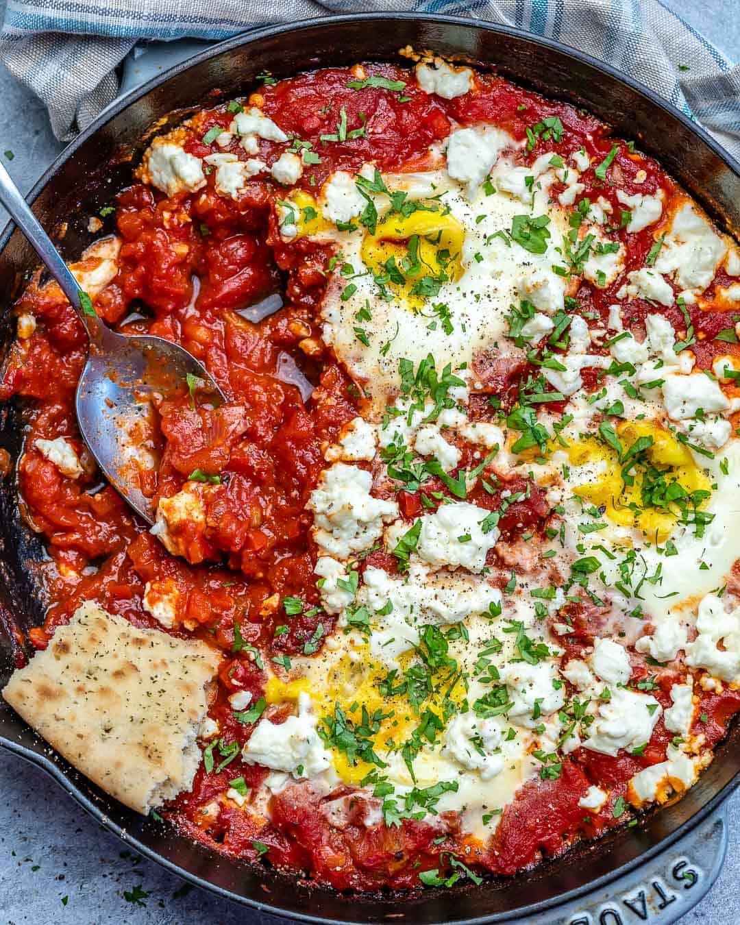Top view of easy shakshuka with feta with spoon in skillet