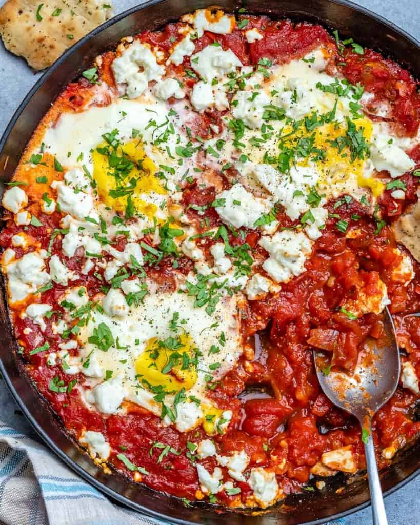 close up top view of shakshuka with spoon in skillet