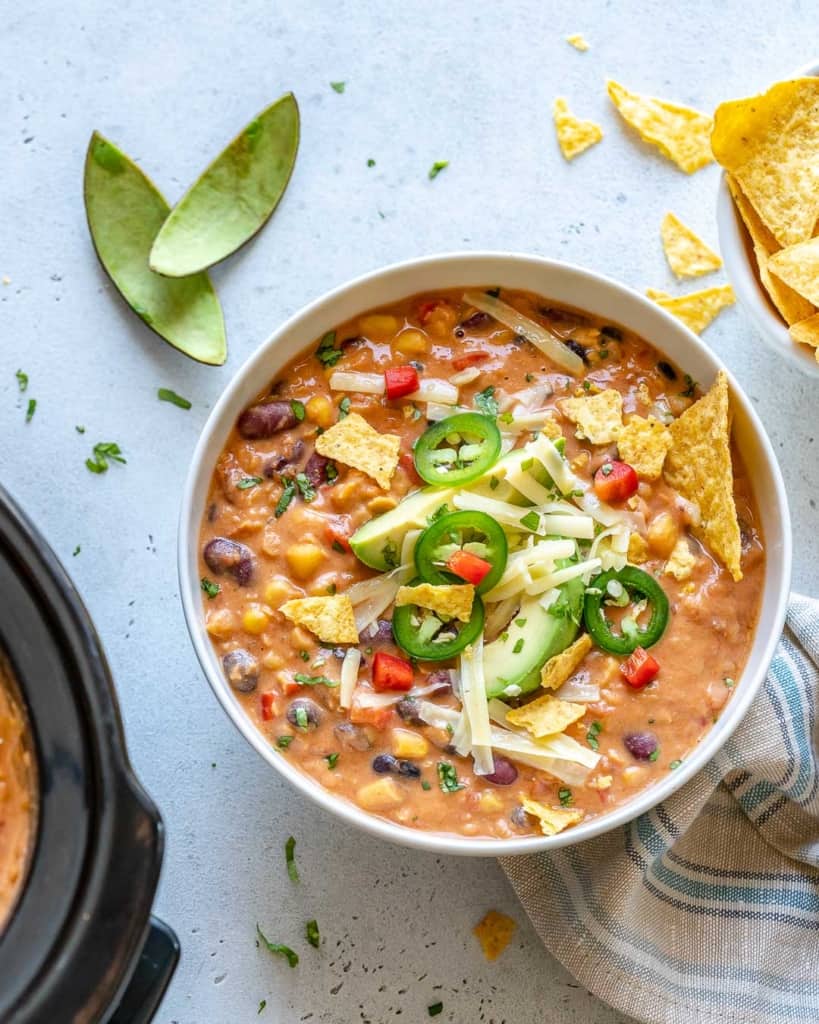 top view tortilla soup in a white bowl with lime wedges on the side 