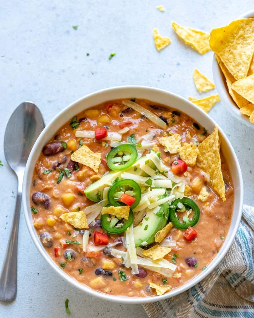 a spoon next to a white bowl of tortilla soup