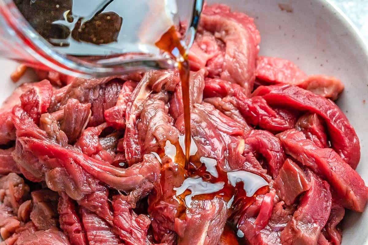 beef being marinated in a bowl.