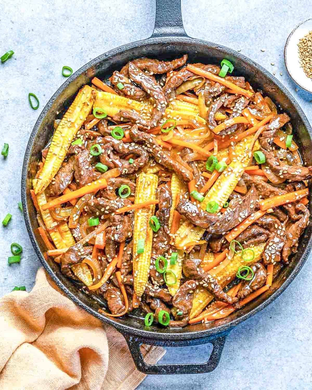 A skillet with beef stir-fry and veggies.