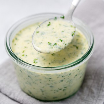 side shot of cilantro lime dressing in a jar with spoon full of dressing