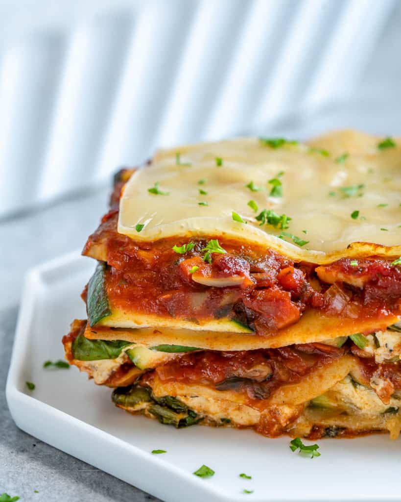 Close up view of slice of vegan lasagna with zucchini on white plate