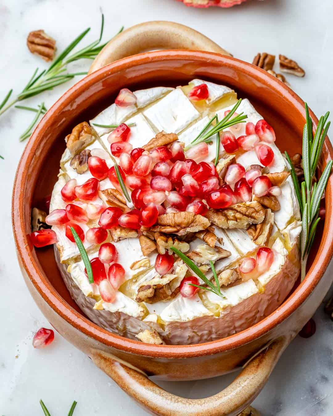 Baked brie with pomegranates, pecans, rosemary, and honey toppings