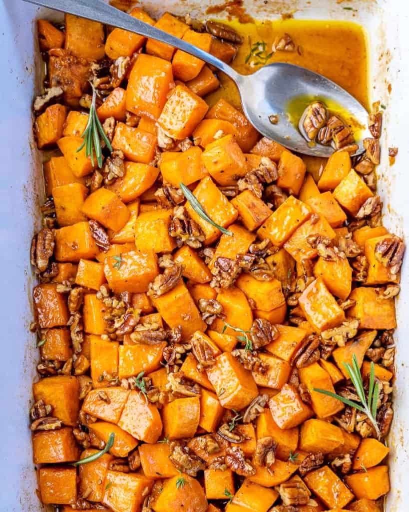 Top down view roasted sweet potatoes in a baking dish with a spoon.