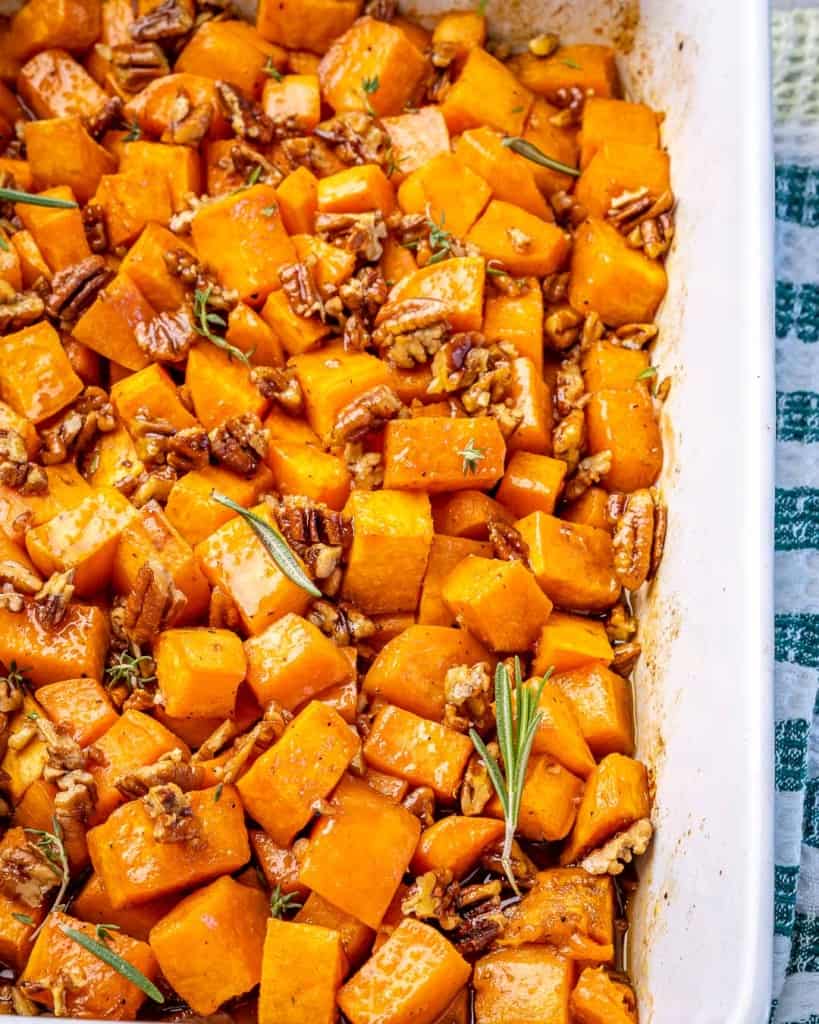 A white dish of roasted sweet potatoes on a cloth. 