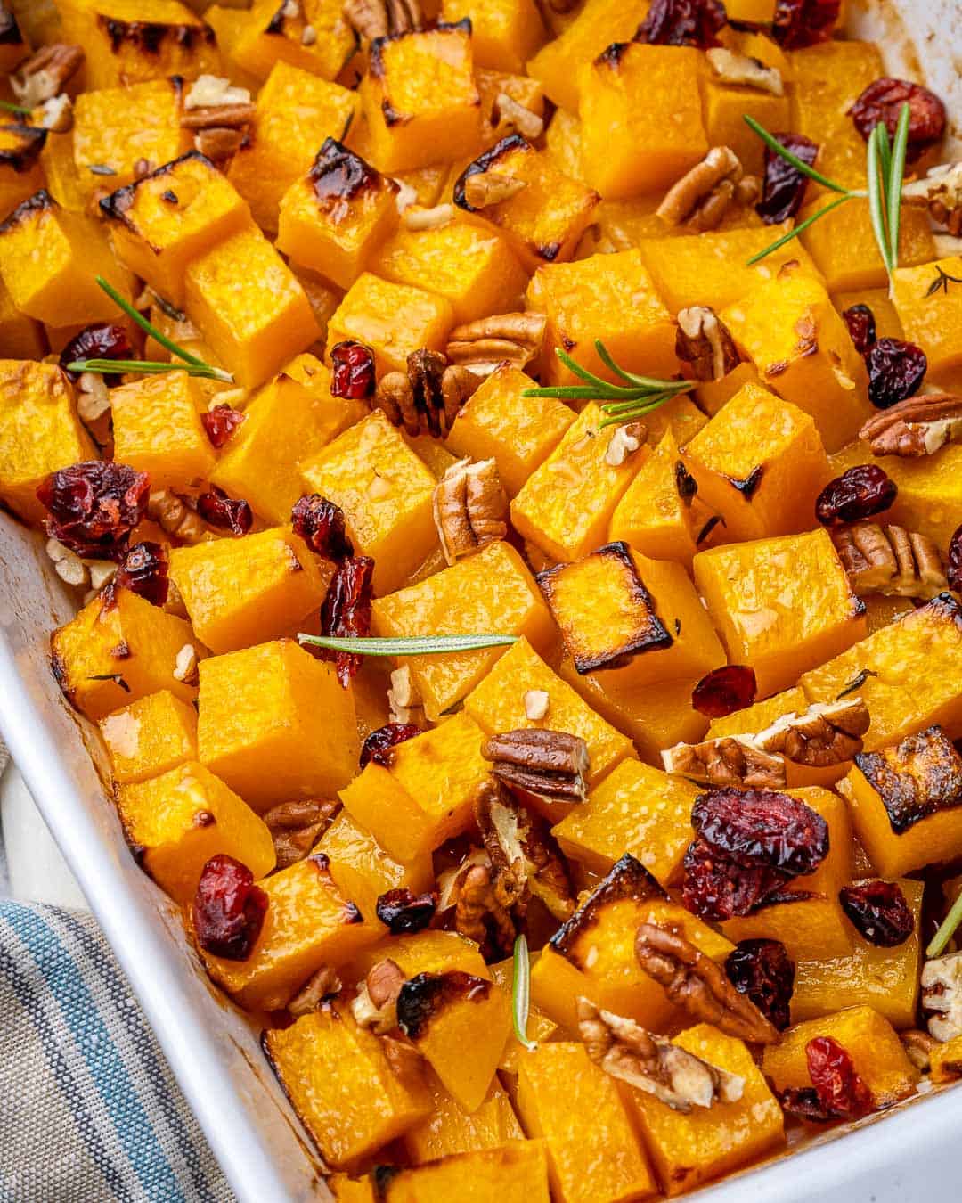 Close view of maple roasted butternut squash in white baking dish