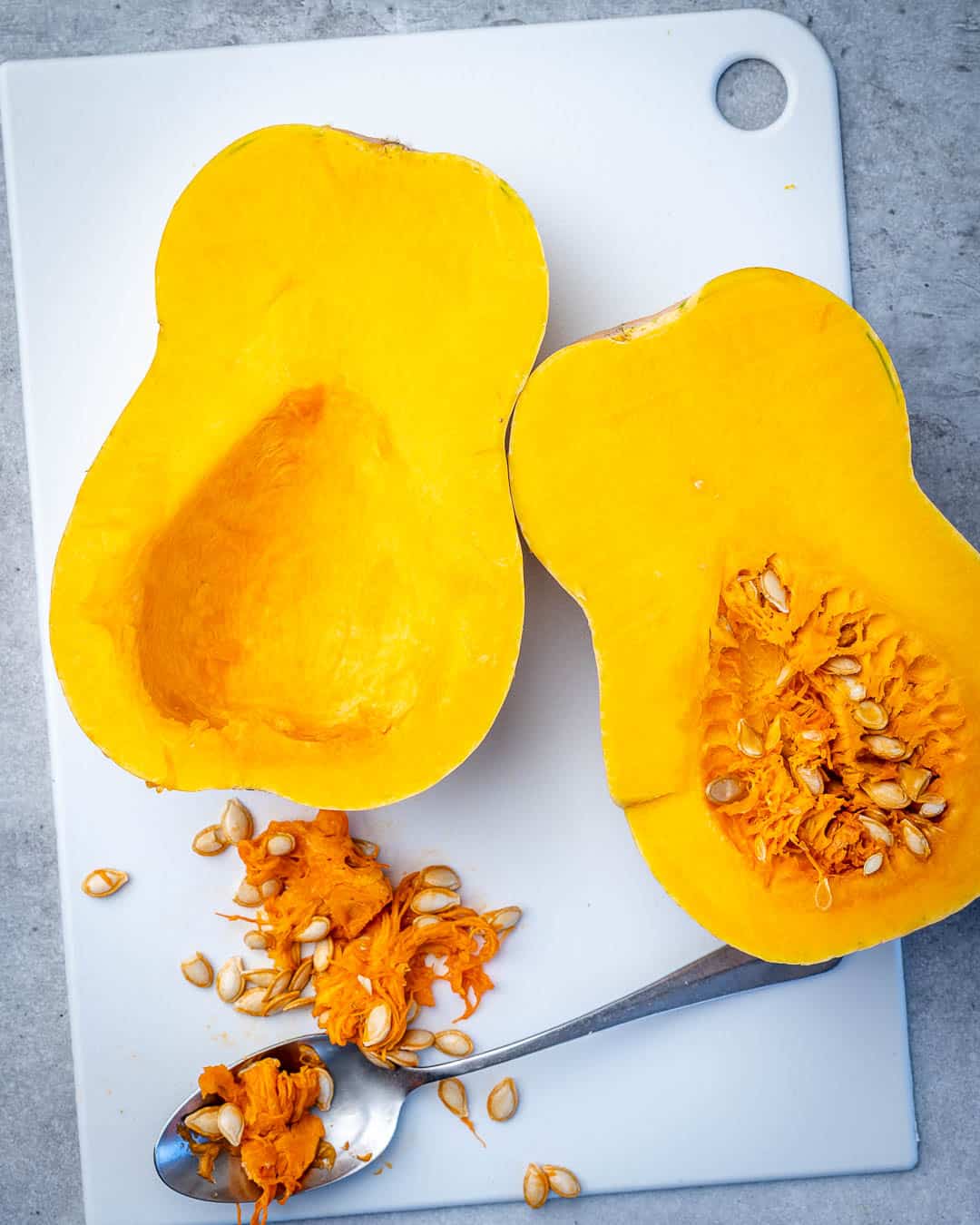 Half a butternut squash with seeds and half with seeds removed.