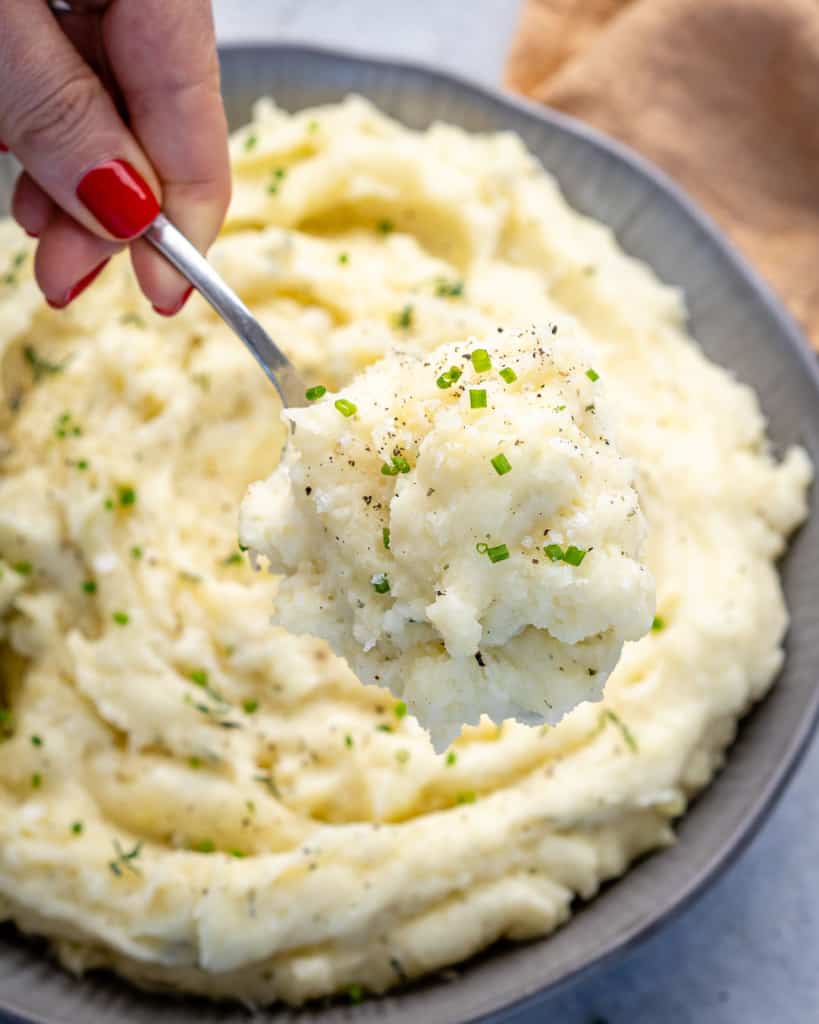 hand scooping a spoonful of mashed potatoes 