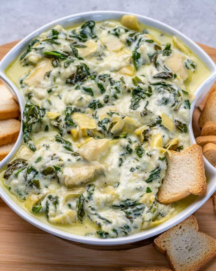 Top down shot of crockpot spinach artichoke dip in a bowl with crackers. 