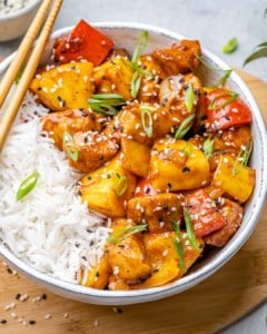 side shot of sweet and sour chicken with rice in a white bowl