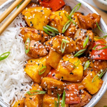 close up of sweet and sour chicken with rice in white bowl