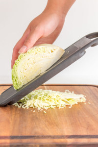 cabbage being shredded using a mandolin