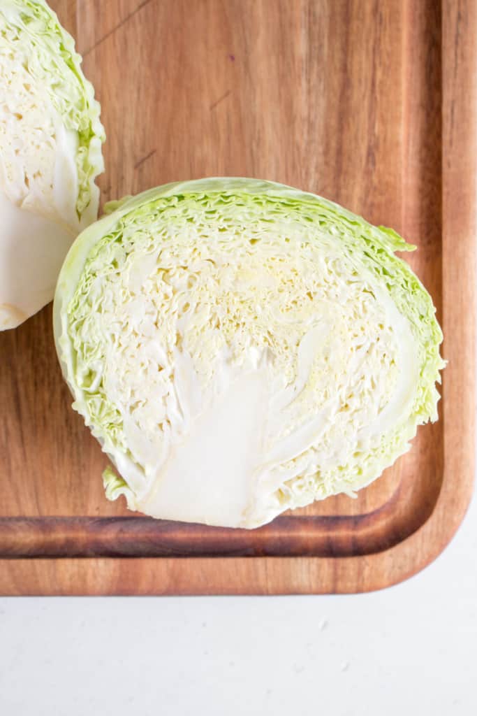 top view of green cabbage cut in half on a cutting board