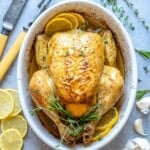 whole roasted chicken in an oval white dish.