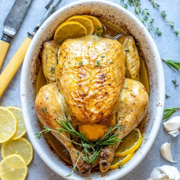 whole roasted chicken in an oval white dish.