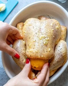 lemon being stuffed into the whole chicken.