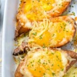 close up view of 3 baked potatoes with eggs in a white dish