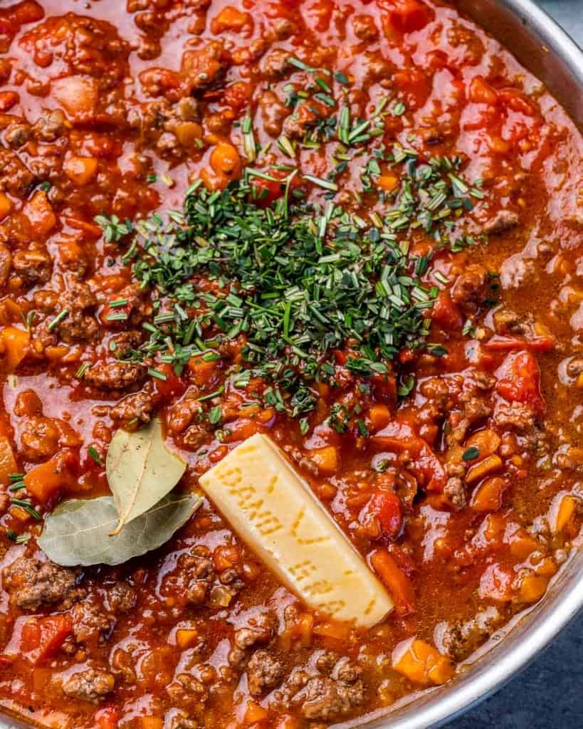 Adding herbs and parmesan to bolognese. 