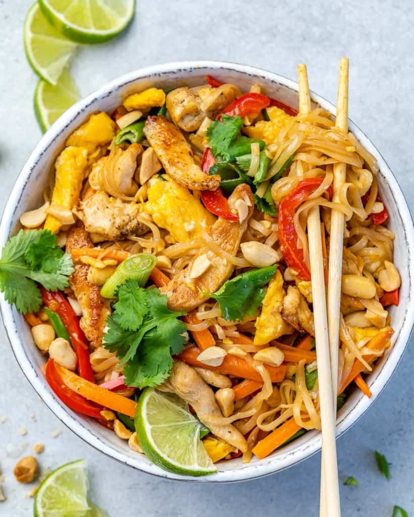 A bowl of chicken pad thai with a pair of chopsticks on top.