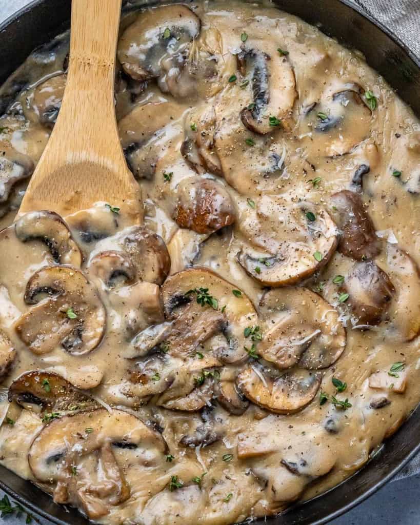 Mushrooms in sauce in cast iron skillet with spoon