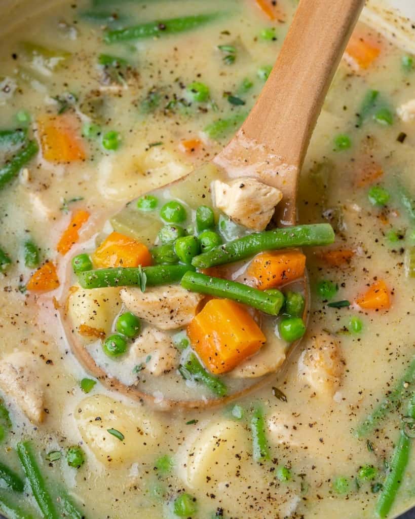 A wooden spoonful of chicken and gnocchi soup.