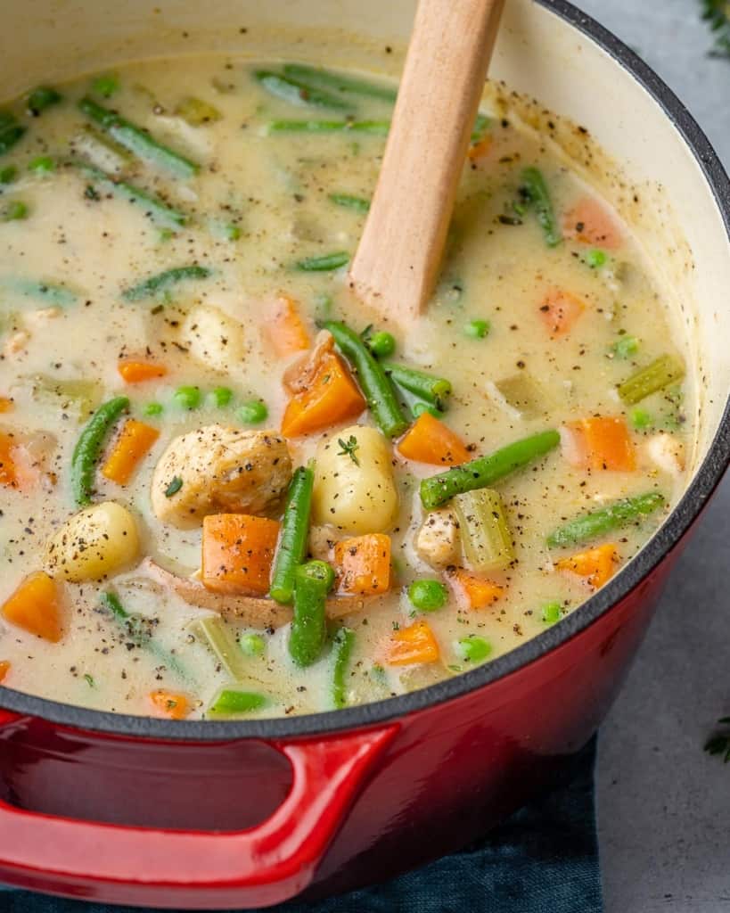 A red Dutch oven filled with chicken gnocchi soup.