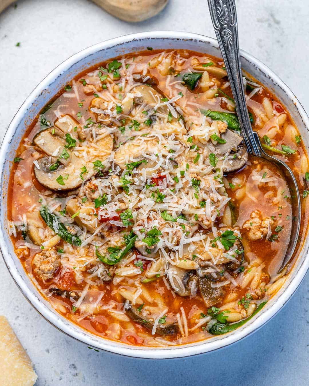 close up view of chicken orzo soup with lemon and mushrooms with spoon