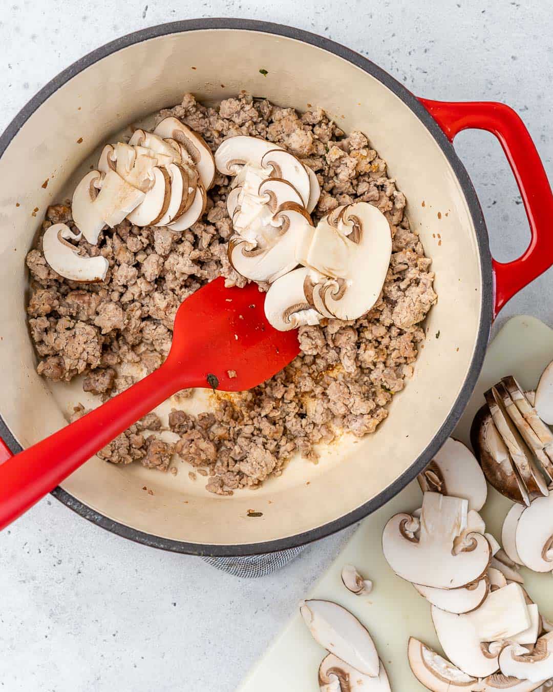 ground chicken and mushrooms cooking. in dutch oven with spatula