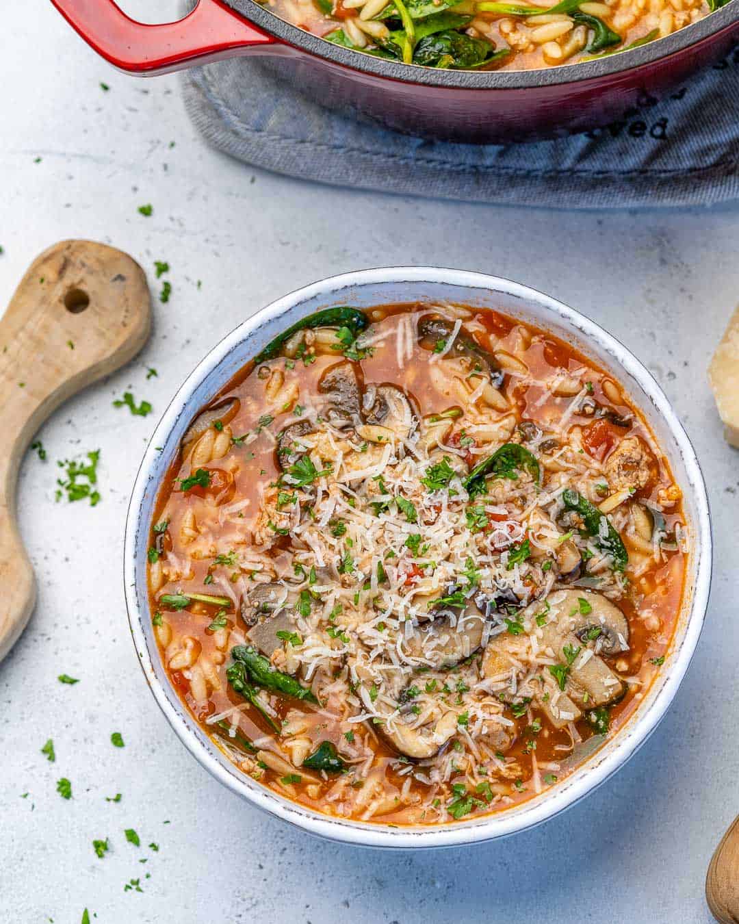 one bowl full of chicken orzo soup with cheese and mushrooms 