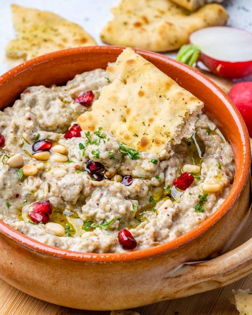side shot of baba ganoush with pita bread in the dip
