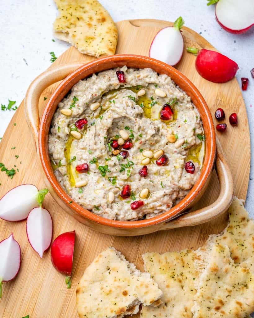 top view baba ganoush dip on a board with side of pita bread