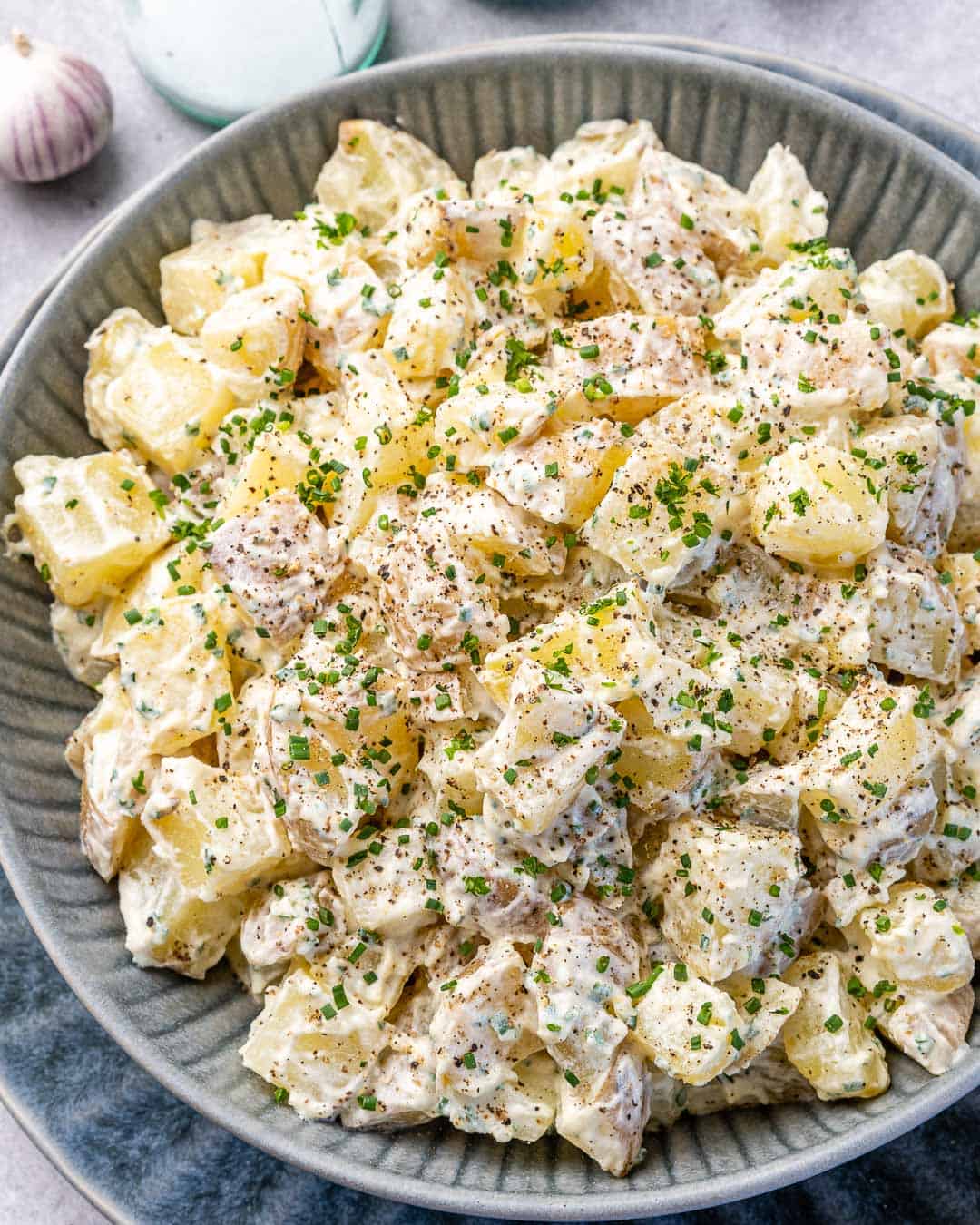 Topview of gray bowl filled with easy mustard potato salad with salt and pepper on counter