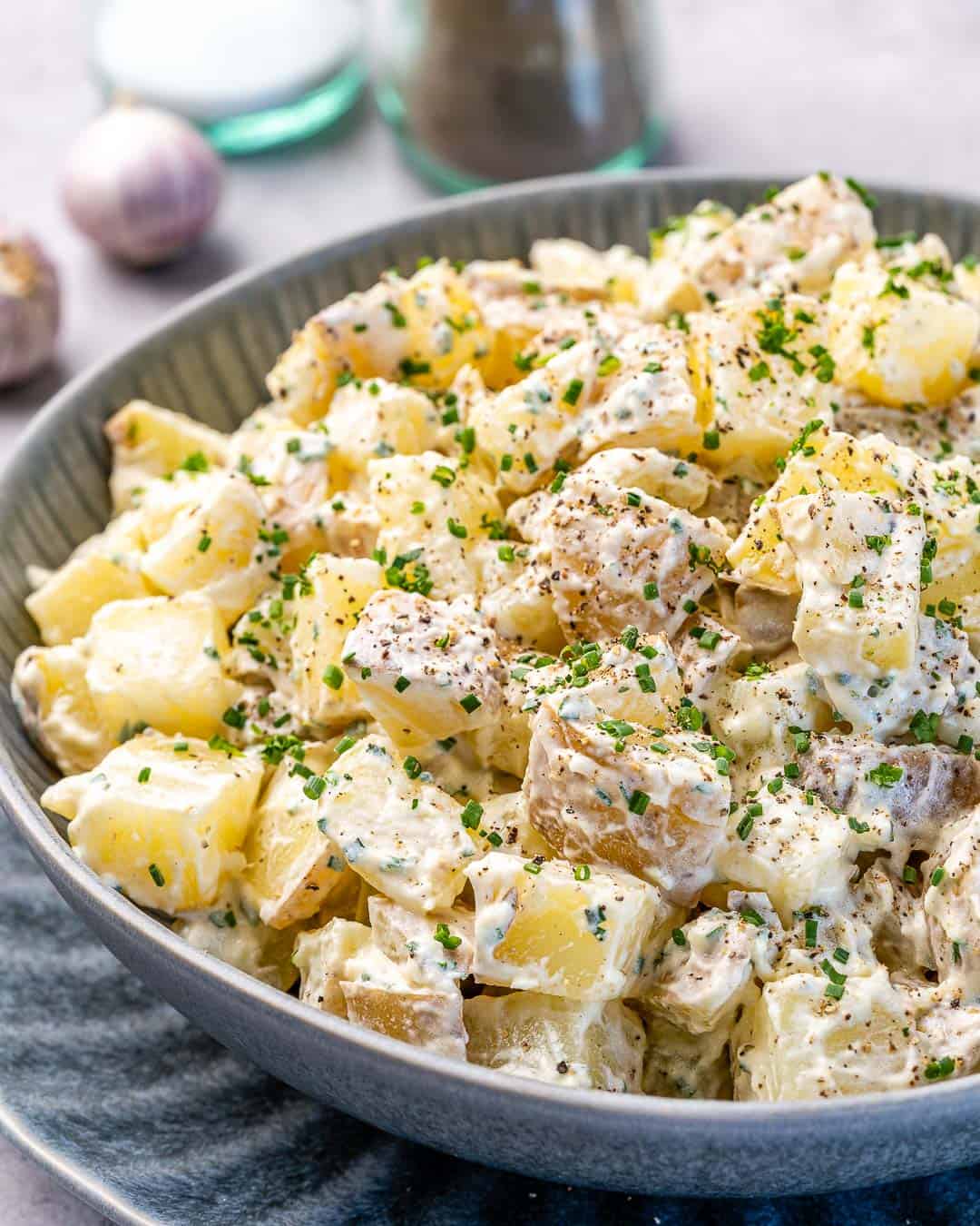 Bowl of healthy mustard potato salad with salt and pepper in background