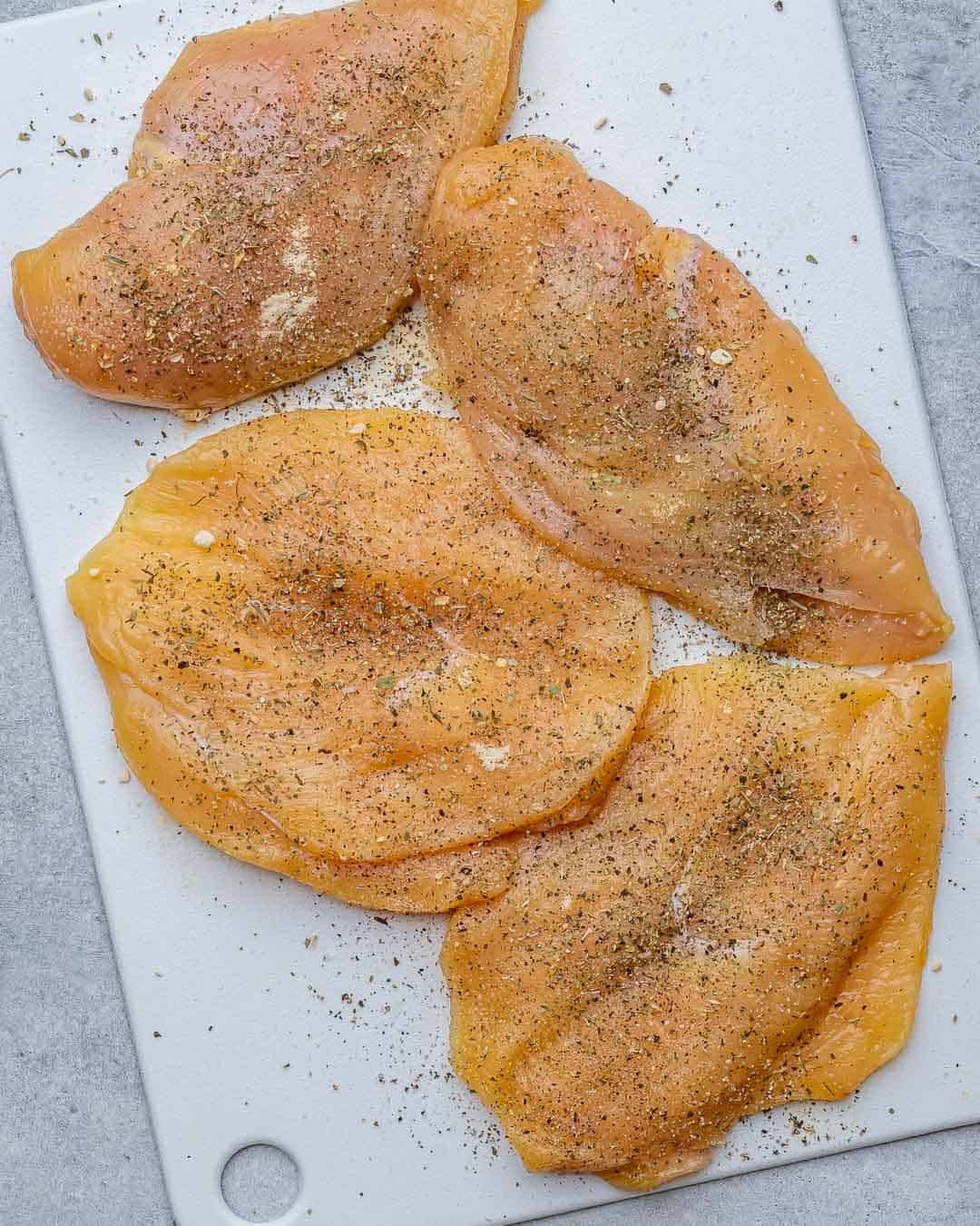 seasoned raw chicken on a white cutting board