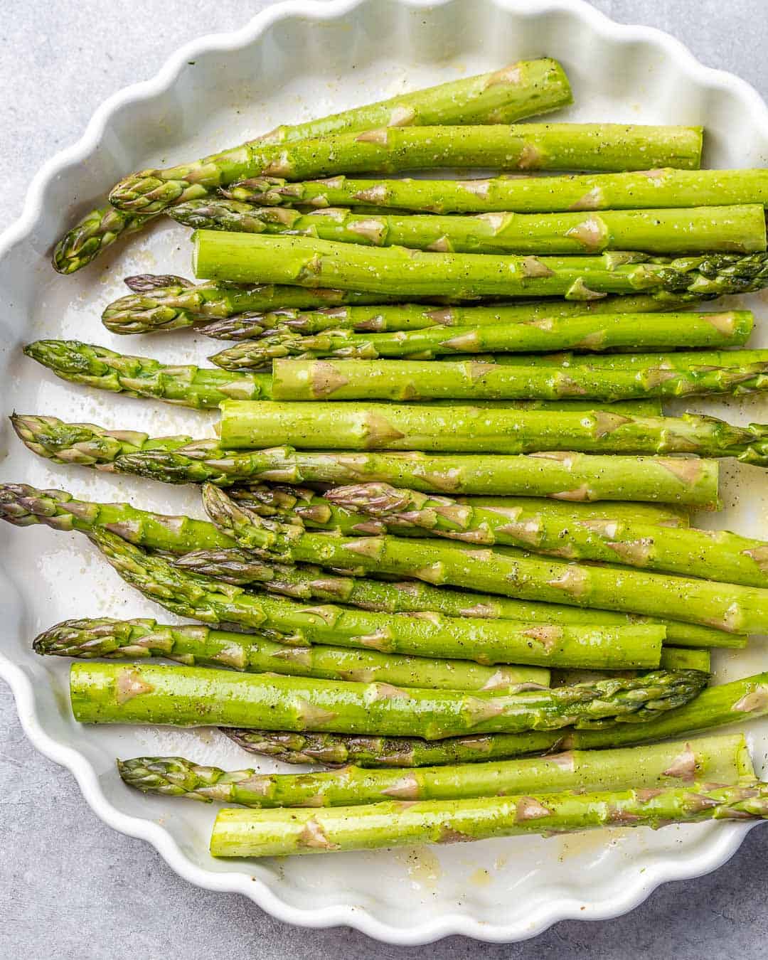 uncooked asparagus on a white dish