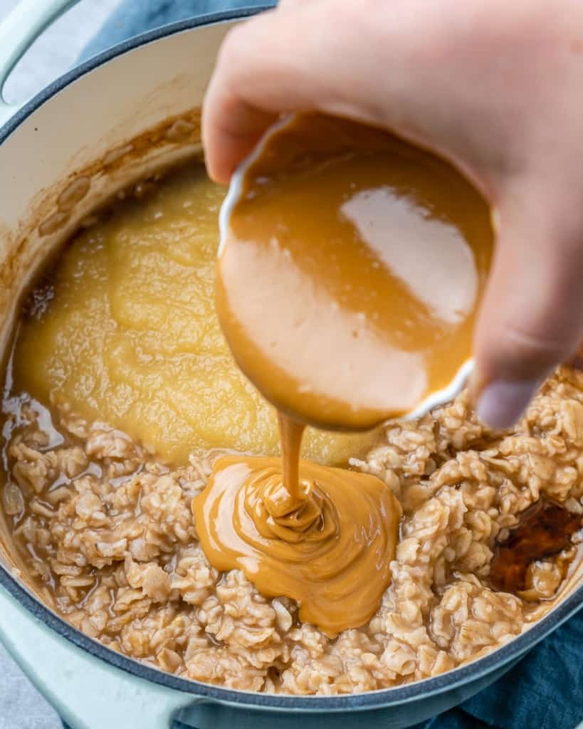 Pouring peanut butter onto oats.