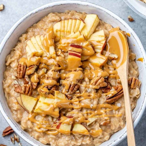 top view oatmeal bowl with apples peanut butter garnish with wooden spoon in bowl