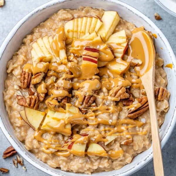 top view oatmeal bowl with apples peanut butter garnish with wooden spoon in bowl